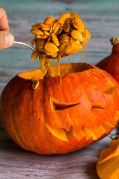 istock Gets a spoonful of pumpkin seeds from Jack's lantern (pumpkins for Halloween) 856631690