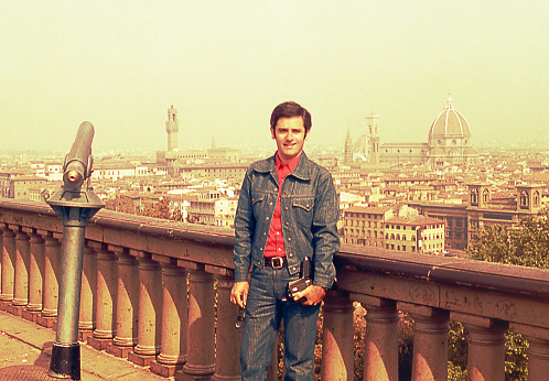 Vintage image from the seventies featuring a man looking at camera with a panoramic view of Florence , Italy in the background.