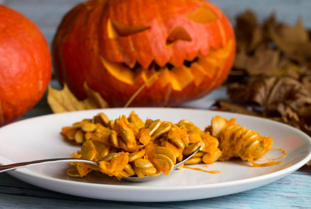 Halloween. All Saints' Day. pumpkin seeds on the white plate on the background of Jack O 'Lanterns. Halloween. All Saints' Day. pumpkin seeds on the white plate on the background of Jack O 'Lanterns. pumpkin throwing up stock pictures, royalty-free photos & images