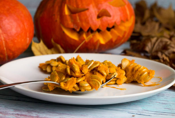 Halloween. All Saints' Day. pumpkin seeds on the white plate on the background of Jack O 'Lanterns. Halloween. All Saints' Day. pumpkin seeds on the white plate on the background of Jack O 'Lanterns. pumpkin throwing up stock pictures, royalty-free photos & images