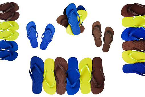Several pairs of multi-colored rubber flip-flops exhibited in a row, isolated.
