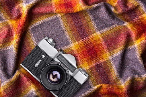 Old retro camera on warm coverlet or bedspread with copy space for your promotional text or advetrisment Cozy domestic atmosphere. Photography conept. Top view of old device.