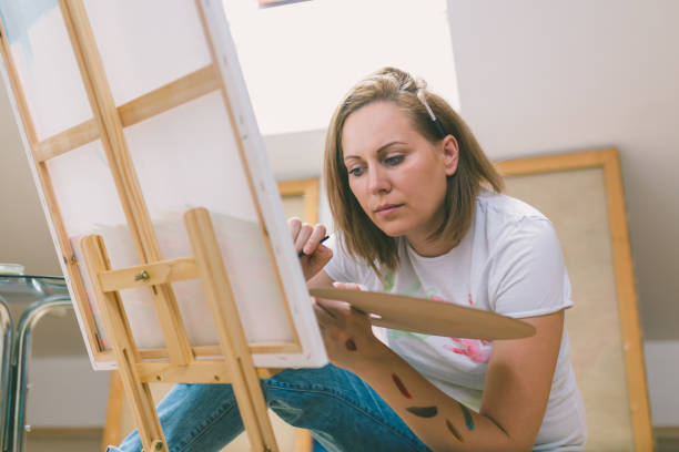 istock Happy young woman paints on canvas 856656074