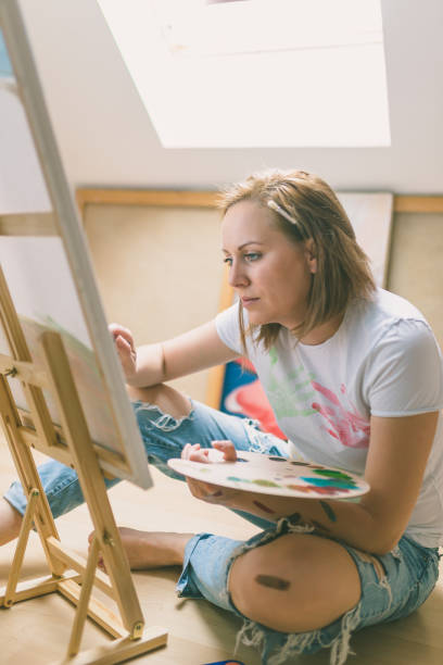 istock Happy young woman paints on canvas 856656514