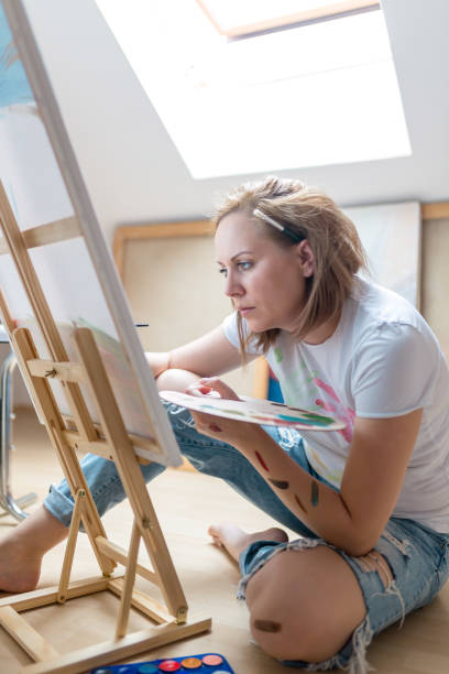 istock Happy young woman paints on canvas 856656806