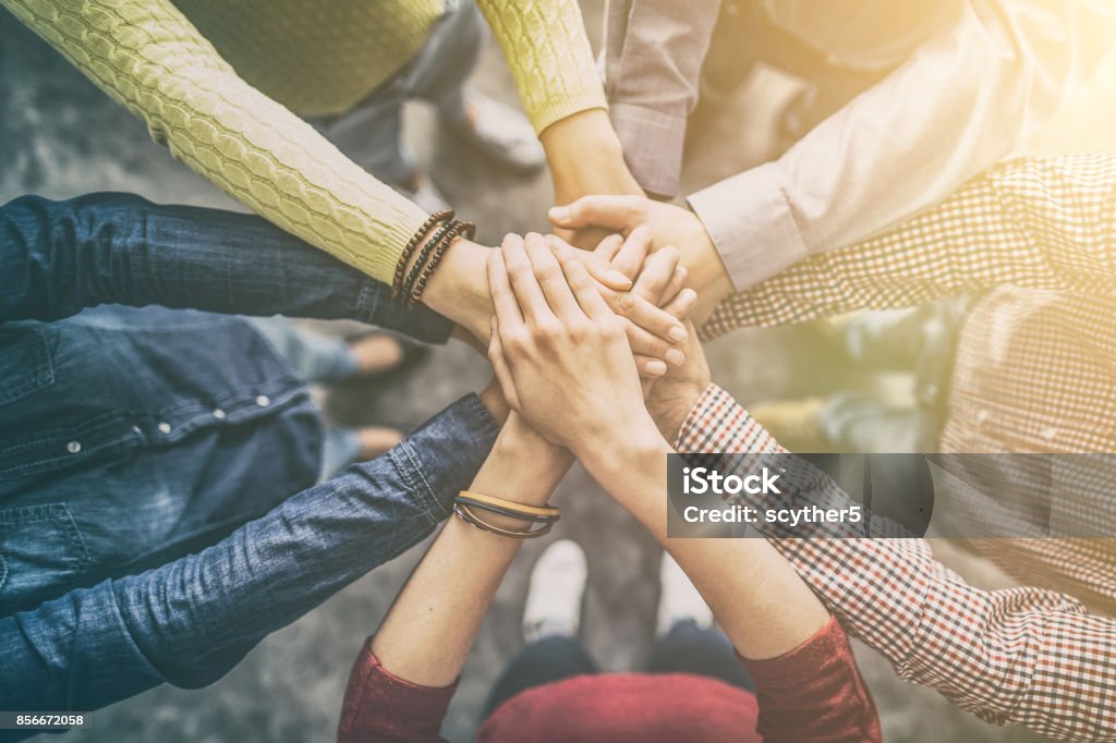 Stack of hands. Unity and teamwork concept. Close up top view of young business people putting their hands together. Stack of hands. Unity and teamwork concept. Holding Hands Stock Photo
