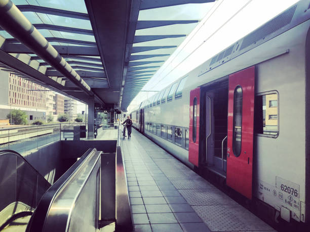 Passenger train cabin interior with empty leather seats with European buildings suggested in window.