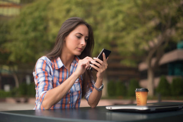 istock Attractive young woman reading a text message on her cell phone. Girl sitting outdoors using smartphone 856676026