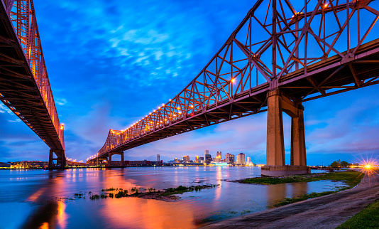 Skyline of New Orleans with Mississippi River and Crescent City Connection Bridge in Louisiana, United States at dusk.