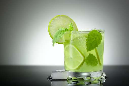 A glass of Mojito with ice, lime wedges and mint