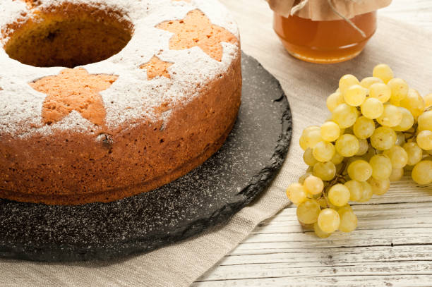 gâteau aux fruits traditionnel maison sur pierre sont décoré avec des raisins et miel pot à une table en bois blanche - fruitcake christmas cake cake raisin photos et images de collection