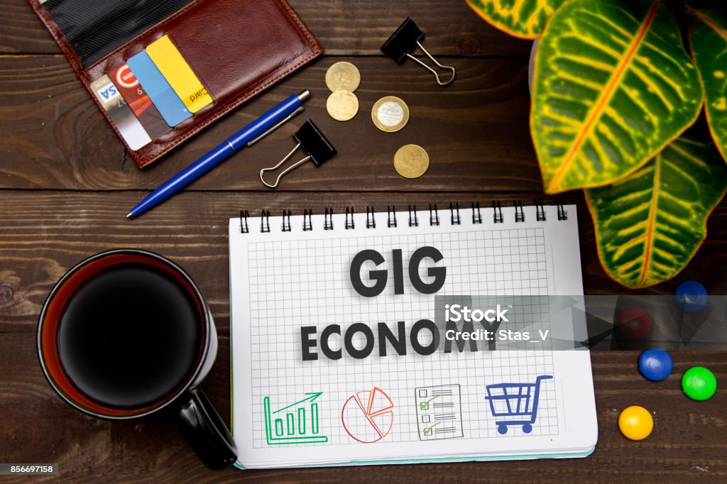 Cuaderno con notas de economía GIG en la mesa de oficina con herramientas. Concepto con los elementos de la infografía. - Foto de stock de Economía gig libre de derechos