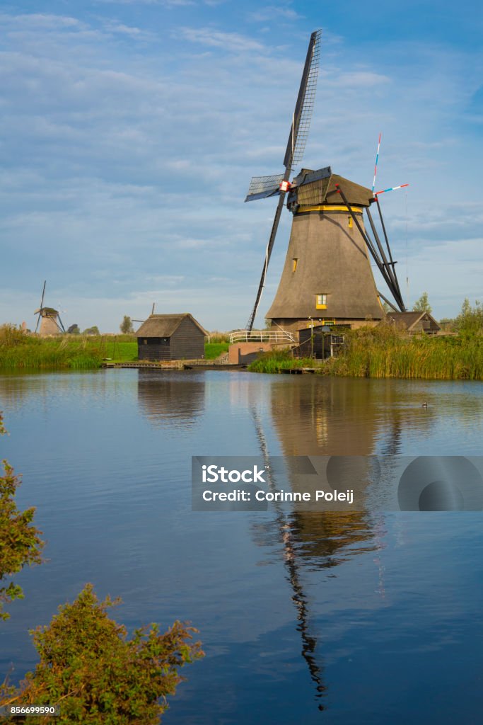 Windmill in Dutch water landscape, Kinderdijk, The Netherlands, against cloudy sky mill in polder landscape, Unesco Heritage, Holland Blue Stock Photo