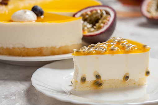 Delicious cheesecake with the passion fruit coulis on the black and wooden background