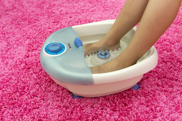 massager del pie de los pies de los niños en un vibrante. baño de pies de masaje eléctrico casero sobre un fondo rosa. relajarse. - health spa women spa treatment massager fotografías e imágenes de stock