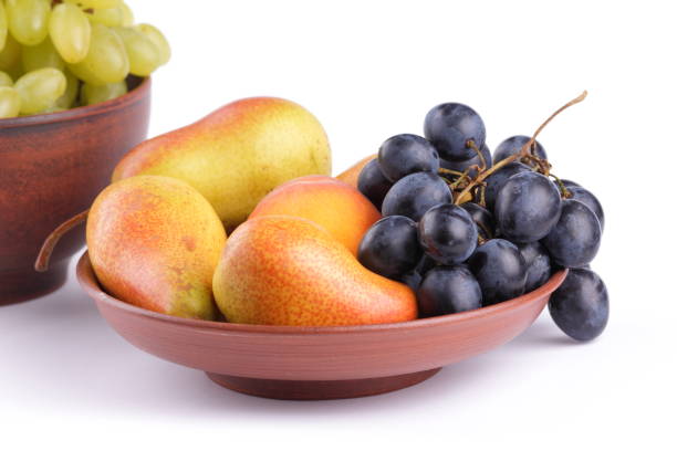 istock Yellow pears, green and blue grapes in a clay plate on a white background 856707108
