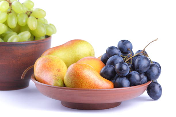 istock Yellow pears, green and blue grapes in a clay plate on a white background 856707156