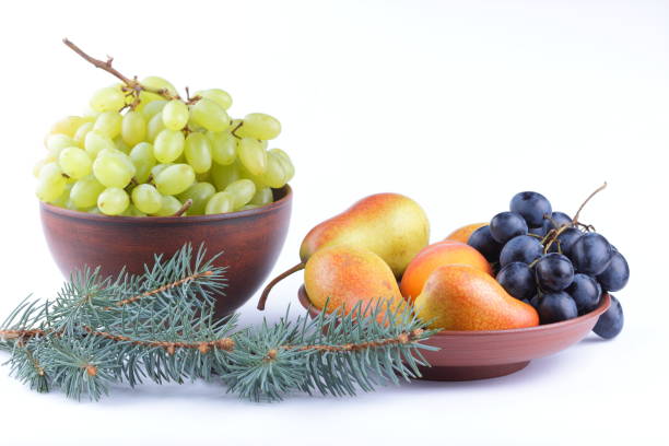 istock Yellow pears, green and blue grapes in a clay plate with Christmas tree branches on a Christmas dinner on a white background 856708044