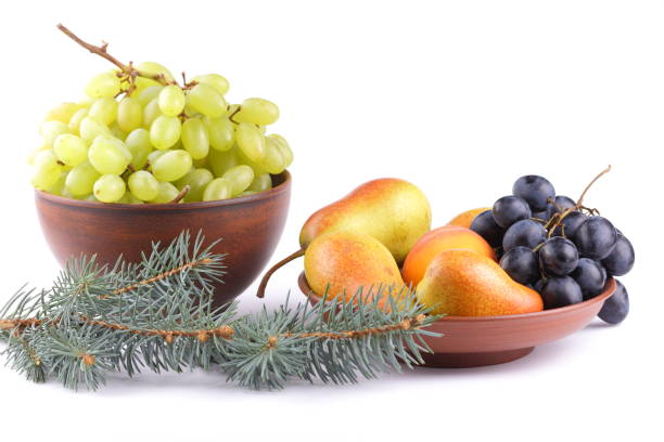 istock Yellow pears, green and blue grapes in a clay plate with Christmas tree branches on a Christmas dinner on a white background 856708092
