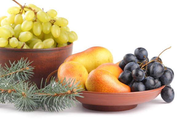 istock Yellow pears, green and blue grapes in a clay plate with Christmas tree branches on a Christmas dinner on a white background 856708166