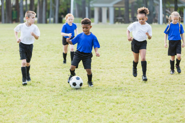 bambini che giocano a calcio - football player group of people running american football foto e immagini stock