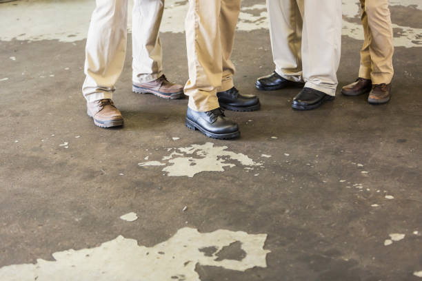 istock Legs of four workers standing on concrete floor 856721792