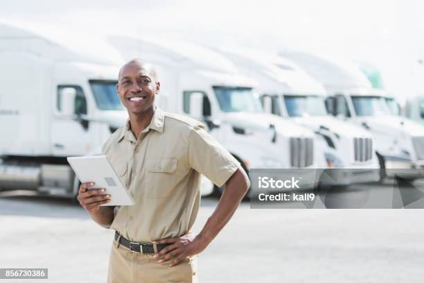 Black Man Standing In Front Of Semitrucks Stock Photo - Download Image Now - Fleet of Vehicles, Manager, Truck