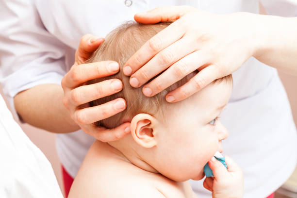 Infant receiving osteopathic treatment of her head Seven month baby girl's head being manipulated by an osteopath - an alternative medicine treatment osteopath photos stock pictures, royalty-free photos & images