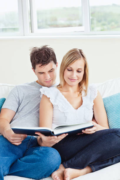 istock Smart couple reading a book together sitting on the sofa 856743926