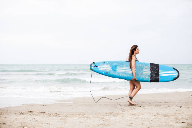 istock Woman on the beach go surfing into the sea waves 856750004
