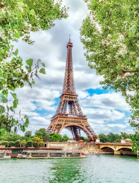 istock Classic view on Eiffel Tower through green poplar foliage over Seine river in Paris. Beautiful summer morning scenery. Vertical orientation. Eiffel Tower is famous travel destination in Europe. 856756598