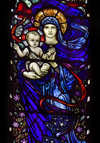 Detail of a Victorian stained glass window of the Virgin Mary and infant Jesus Christ in an ancient English village parish church. Bibury, Gloucestershire