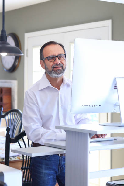 istock Latino Businessman Works At Standing Computer Desk At Home 856780738