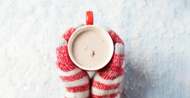 Photo of female hands in gloves holding hot chocolate