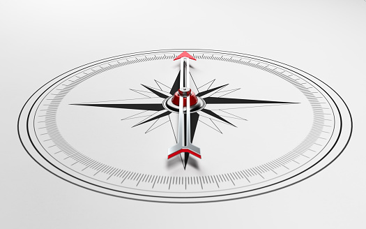 Compass on white background with selective focus. Compass is lit from the upper left corner of composition. Horizontal composition with copy space.