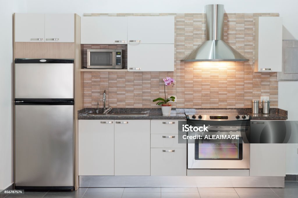 Modern fitted kitchen Small or compact modern kitchen with appliances. Contemporary style. Sparse design. White cabinets. Example of design for small architectural spaces. Front view, horizontal composition. Kitchen background. Kitchen Stock Photo