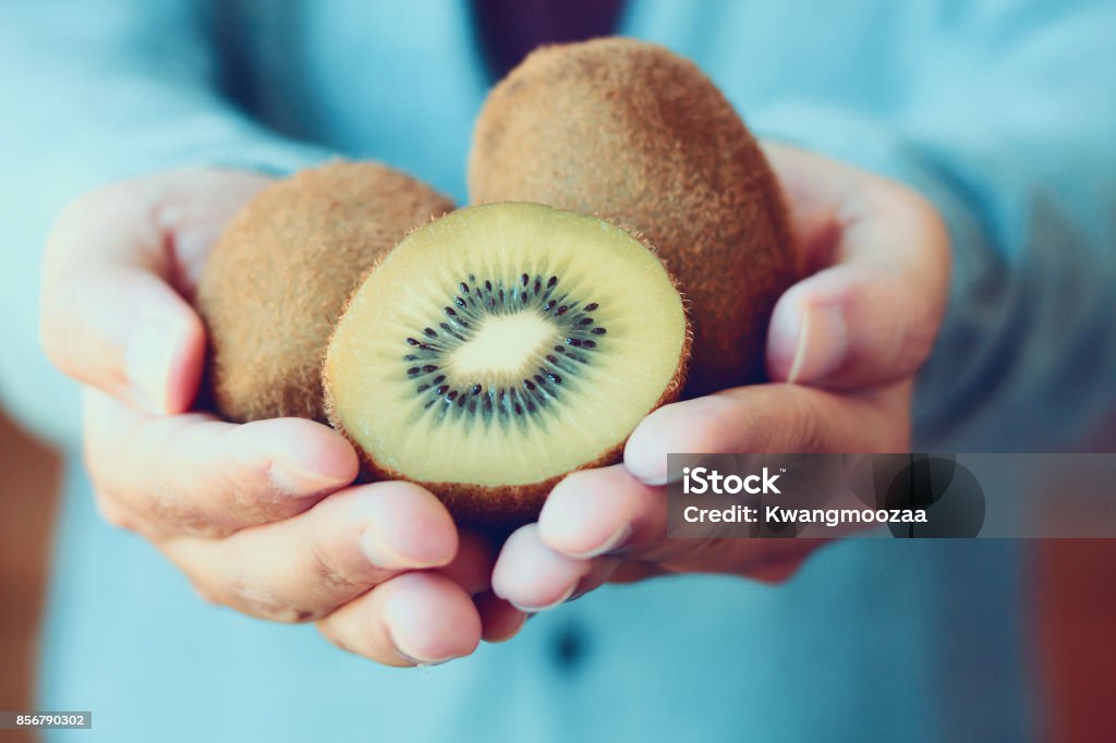 tenendo frutta kiwi fresca - Foto stock royalty-free di Frutto Kiwi