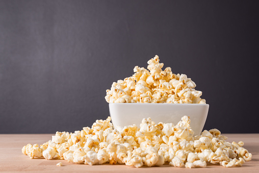 Popcorn in white bowl on wooden background