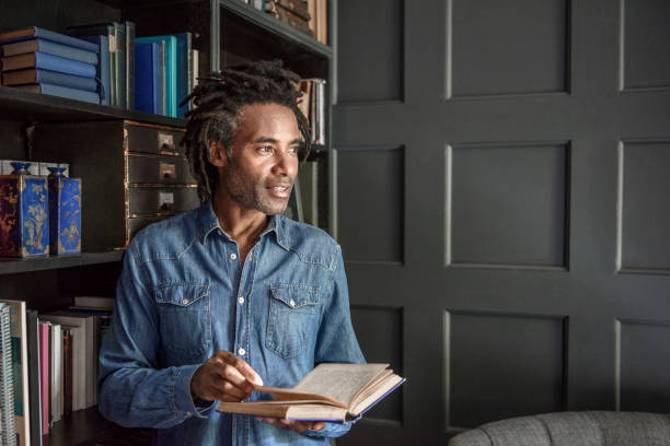 Mature man holding book and looking away in panelled library