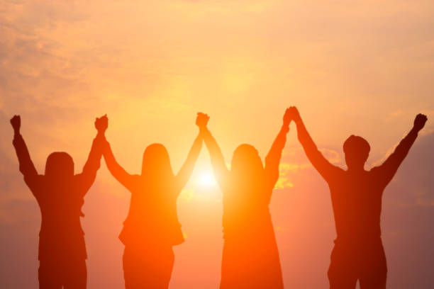 silueta de enfoque suave de equipo de negocio feliz haciendo alta manos en fondo de cielo del atardecer por concepto de trabajo en equipo de negocios - sunset bay oregón fotografías e imágenes de stock