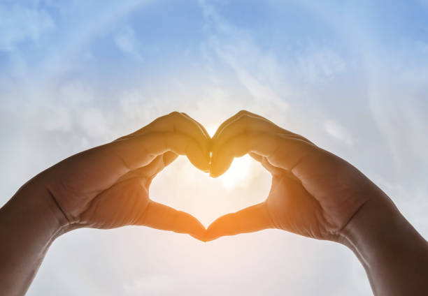 istock Silhouette two hands making form heart shape with sun halo 856795156