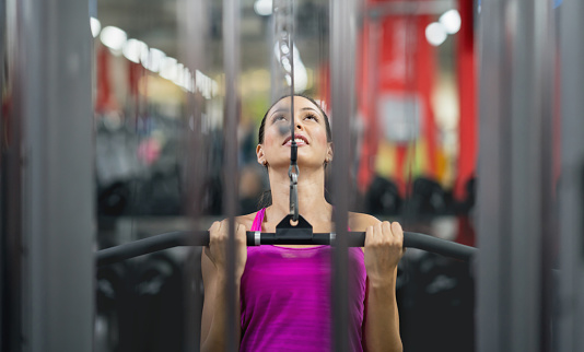 Portrait of a happy woman exercising at the gym on a machine â fitness concepts