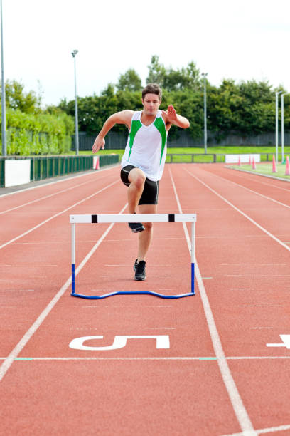 istock Sporty man jumping above hedge during a race 856798134