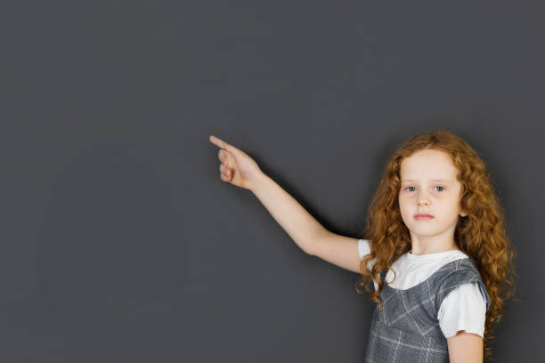 istock Smart child with red glasses points a finger at school board. 856804242