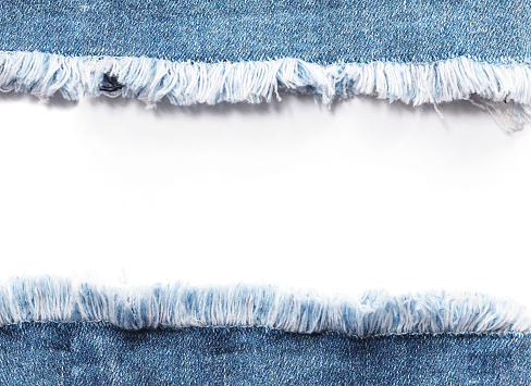 Edge frame of blue denim jeans ripped destroyed torn over white background.