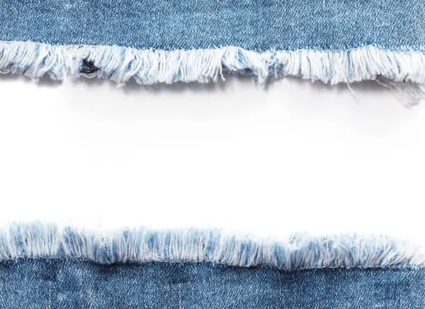 Edge frame of blue denim jeans ripped destroyed torn over white background.