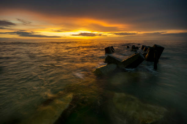 istock a sea breakwater breaking the waves at sunset 856820282