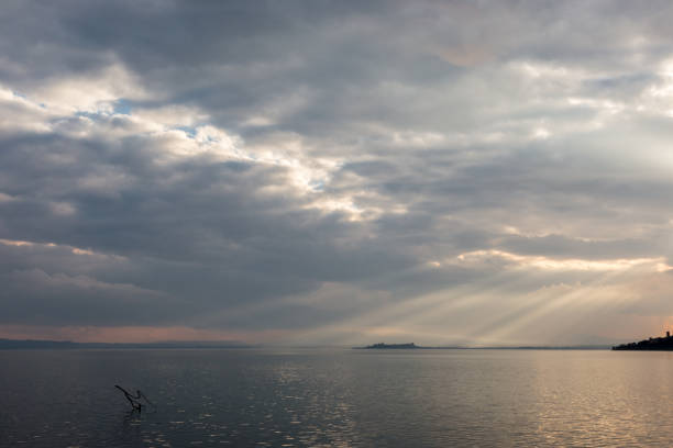 istock Sun rays coming out through the clouds over an island on a lake, with some branches in the foreground 856839864