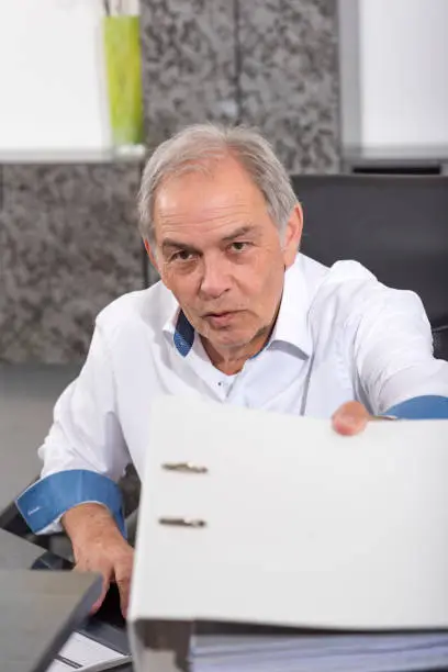 elderly man with a white shirt hands over a file folder