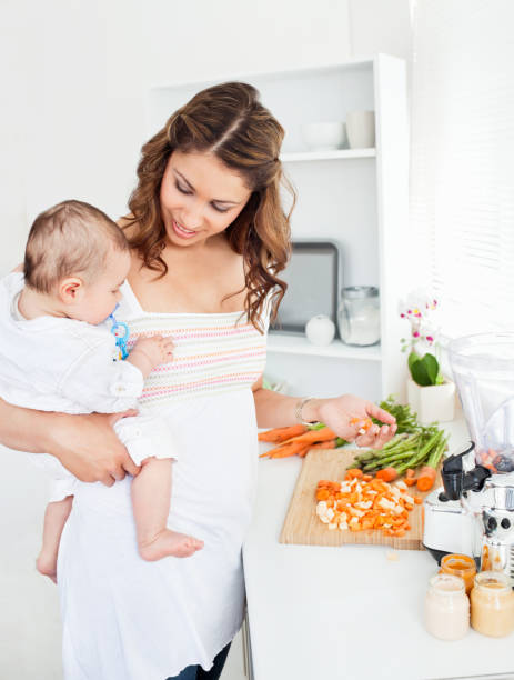 istock Young mother holding her baby while preparing carrot for lunch 856846020